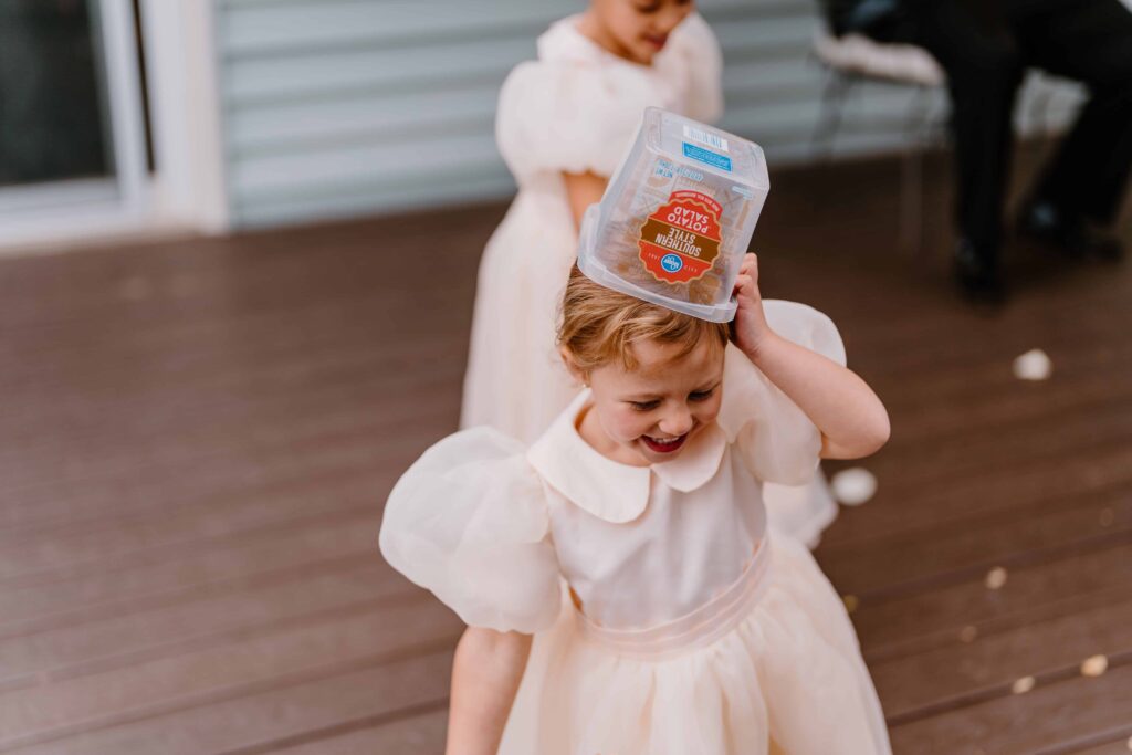 Flower girl walks around with a container on her head being silly