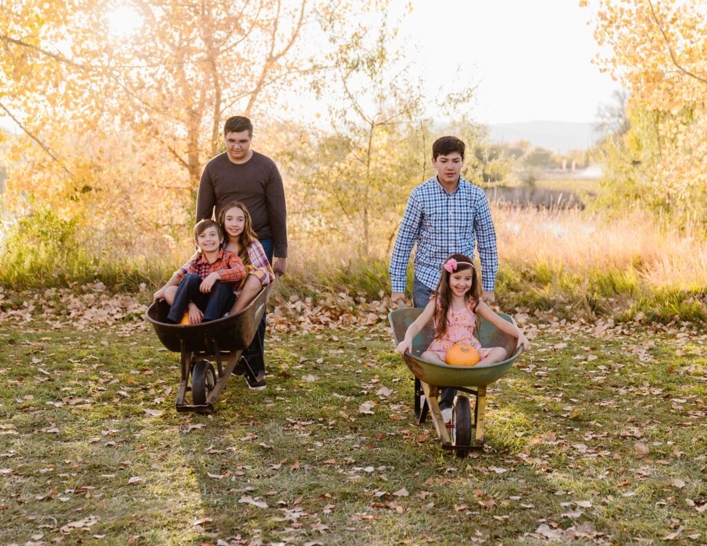 two brothers push their siblings in wheelbarrows
