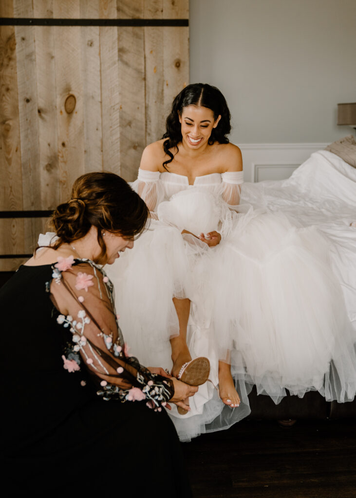 bride putting on earrings while her mom smiles and laughs with her