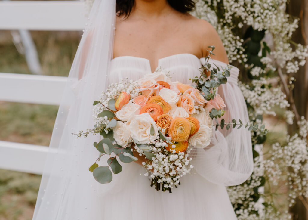 closeup photo of brides bouquet that is orange, peach, and white