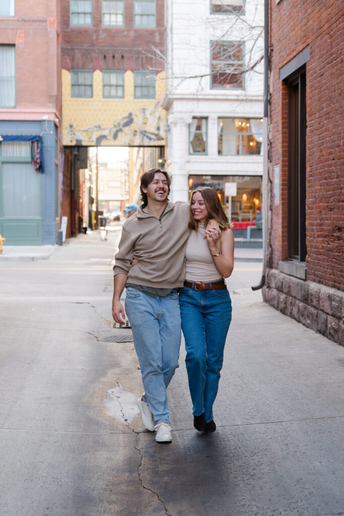 couple walks side by side while laughing together during their Denver Union Station engagement session