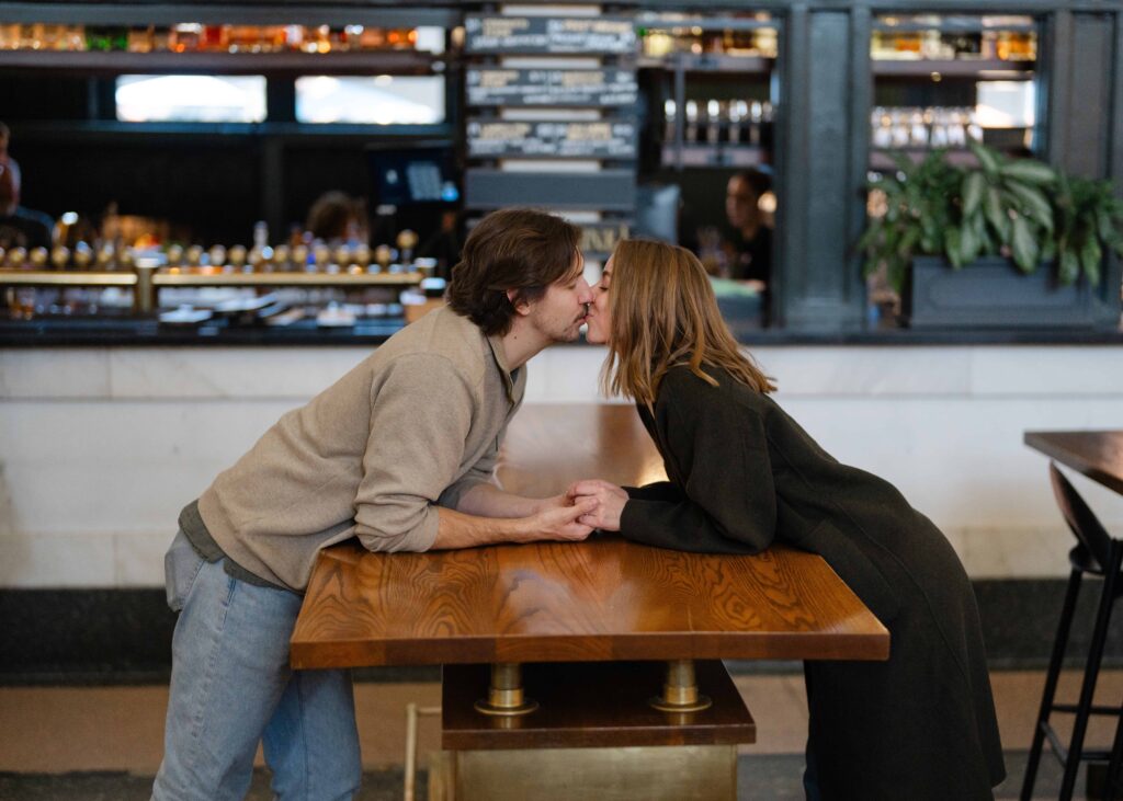 Couple sharing a kiss over a table inside Union Station during their Denver Union Station engagement session.