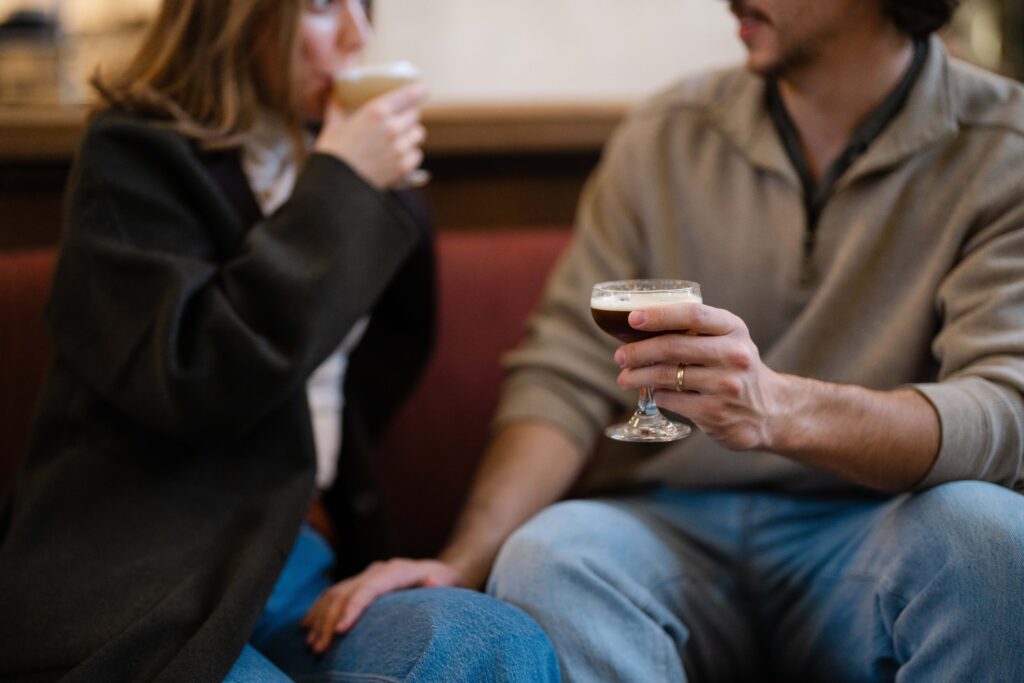 Couple talking on a couch at Union Station, each holding a cocktail.